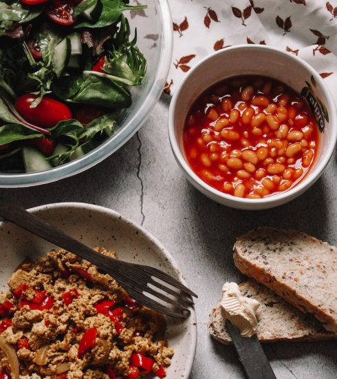 sliced bread with sliced tomatoes and green leaves on white ceramic bowl